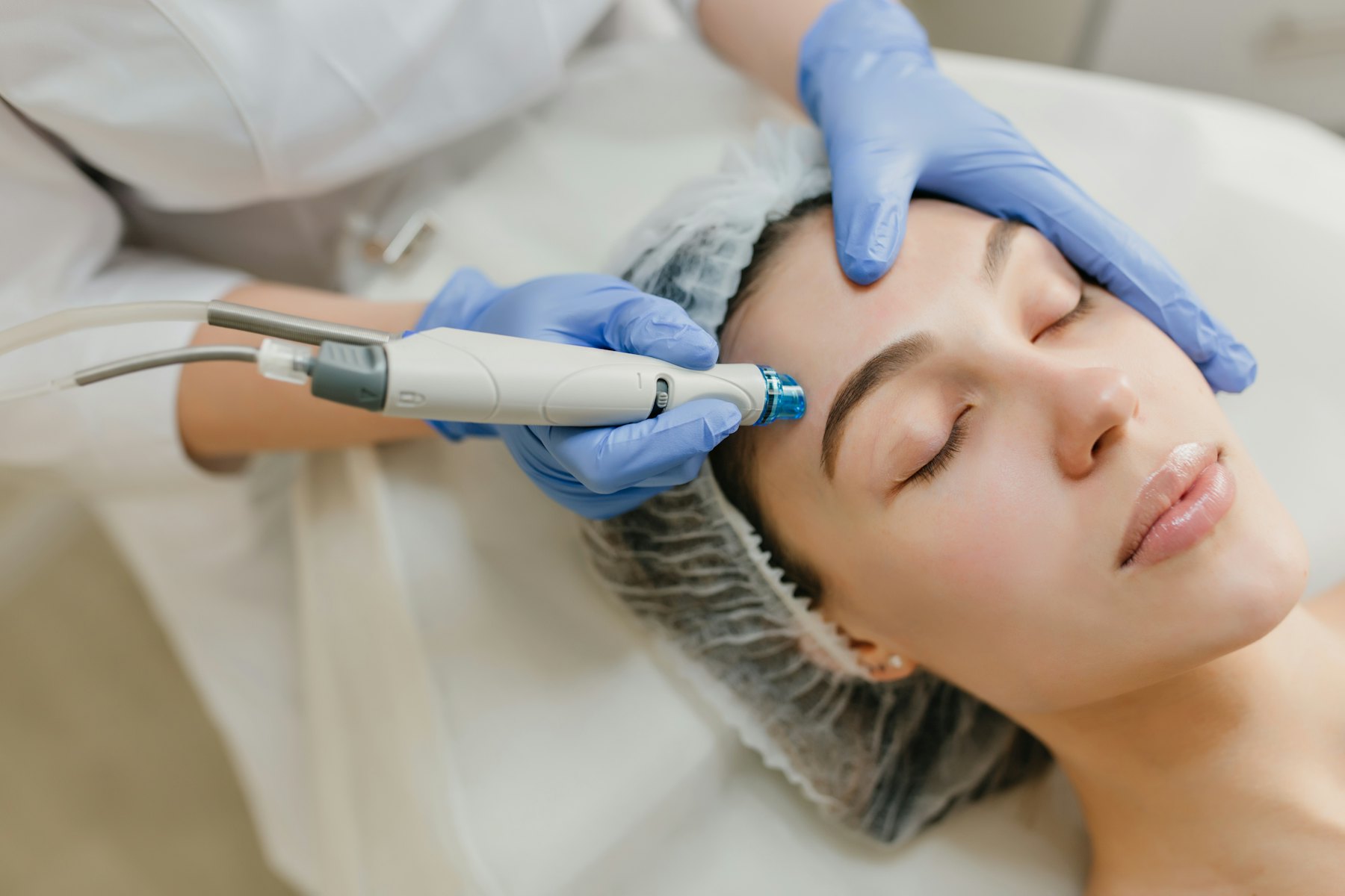 A hydrofacial handpiece being used on a client’s forehead